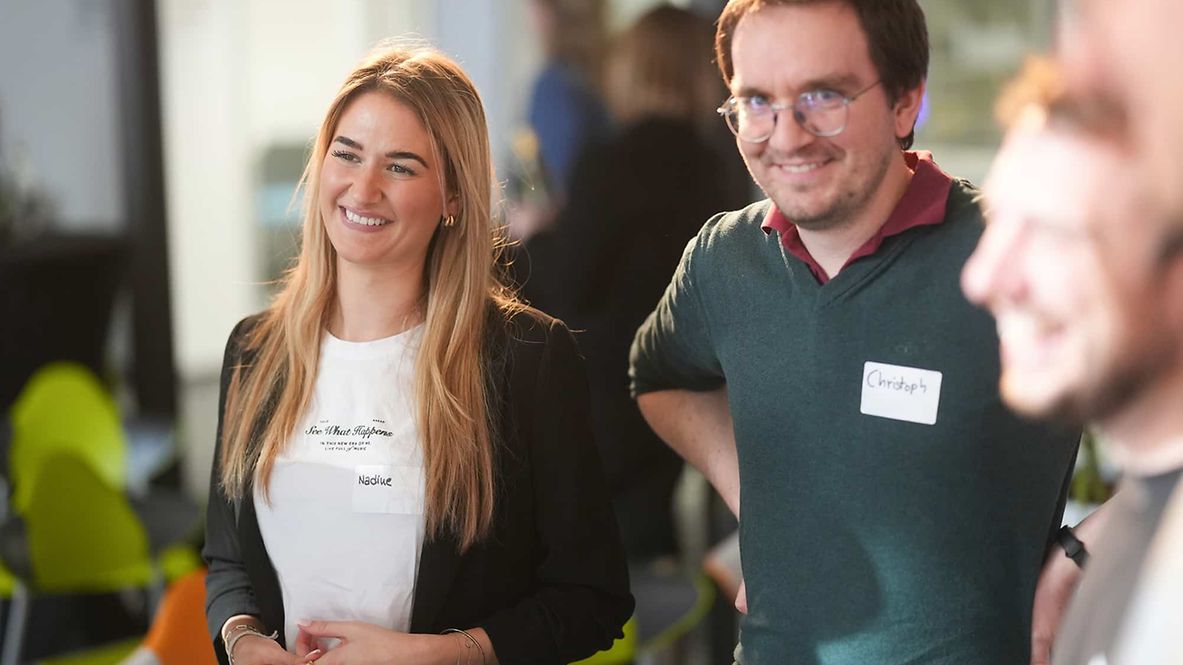 Ein Mann und eine Frau stehen nebeneinander und lächeln in die Kamera