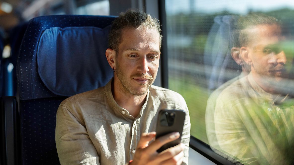  Reisender nutzt ein Smartphone im ICE 3neo mit mobilfunkdurchlässiger Scheiben