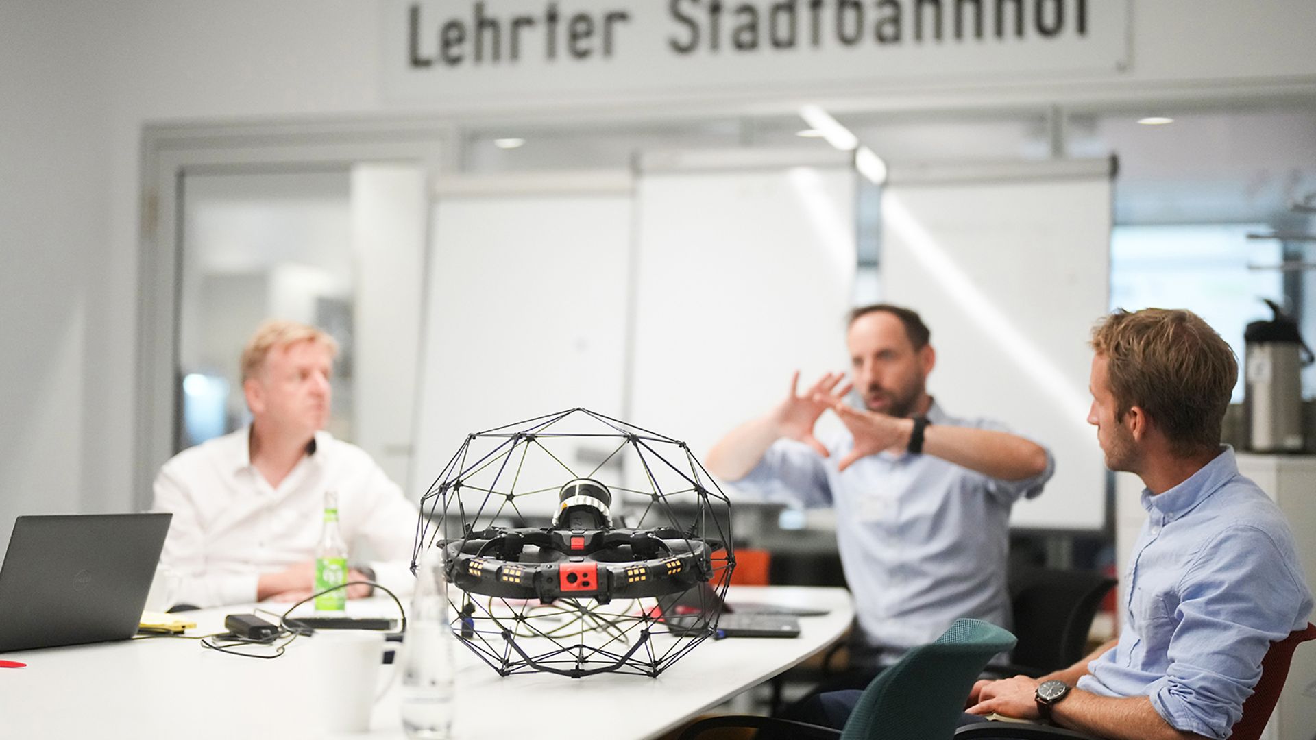 Three men are sitting at a table and talking to each other.